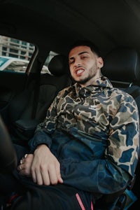 a man in a camouflage jacket sitting in the driver's seat of a car