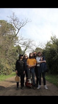 a group of people standing on a dirt road with guitars